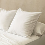 White pillows on a bed against a beige wall.