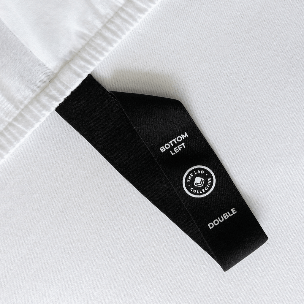 Close-up of a fitted sheet orientation tag labeled “Bottom Left,” designed to simplify bed-making and help identify the correct sheet position.