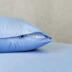 Close-up of a sky blue pillowcase showing a partially open zipper closure revealing white pillow fill