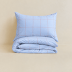 Neatly folded light blue grid-patterned quilt cover with one matching pillowcase resting on top