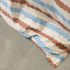 Close-up of a fabric with brown and blue striped pattern on a gray surface.