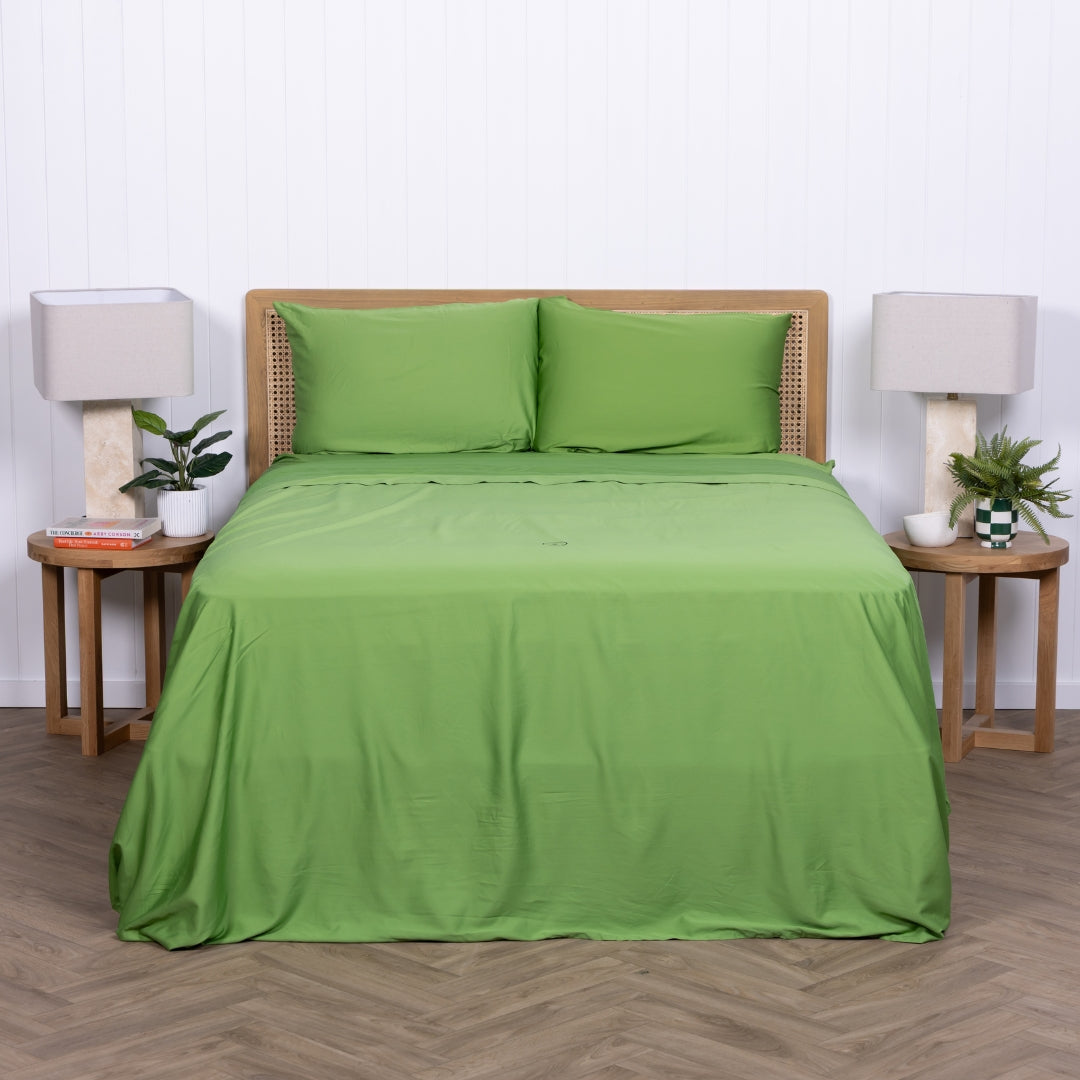 Full view of bed styled in green TLC Palm Cove sheets with bedside tables.