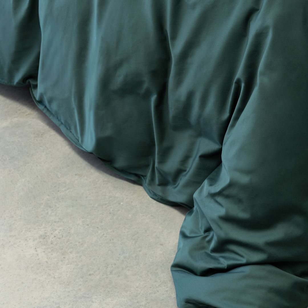 Close-up of green bedding on a bed with a neutral background