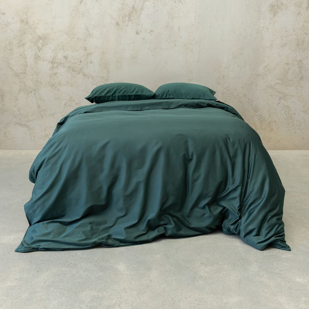 Green bedding set on a bed against a beige wall.