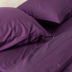 Close-up of purple bedding with pillows on a bed.