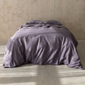 grey bedding set on a bed against a beige wall