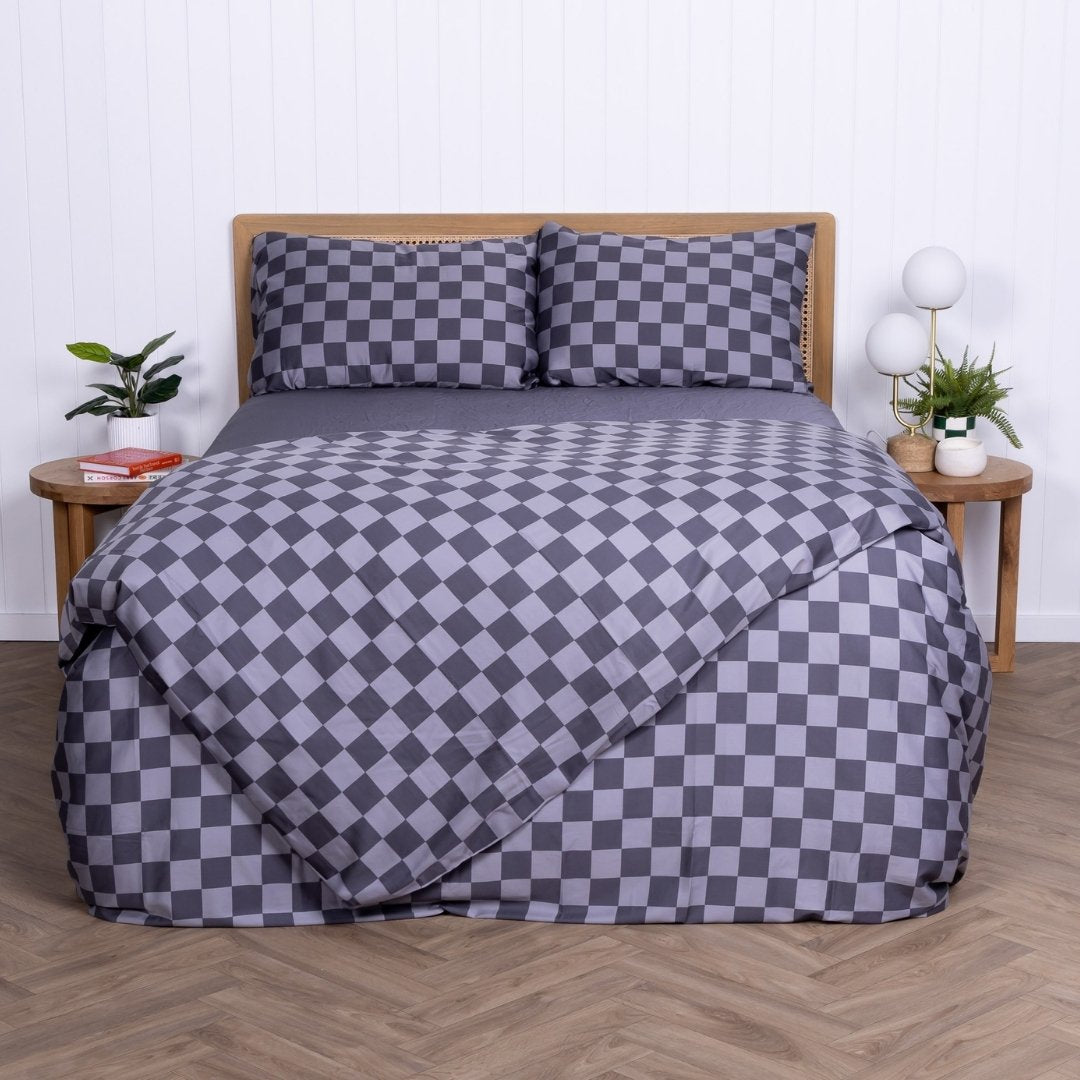 Grey checkered bedspread on a bed with matching pillows in a room setting.
