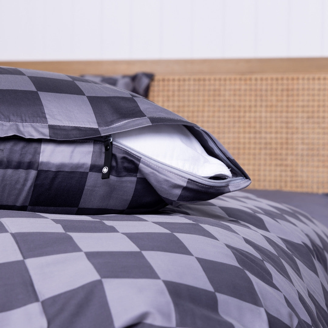 Grey checkered pillowcase on a pillow with a wooden headboard.