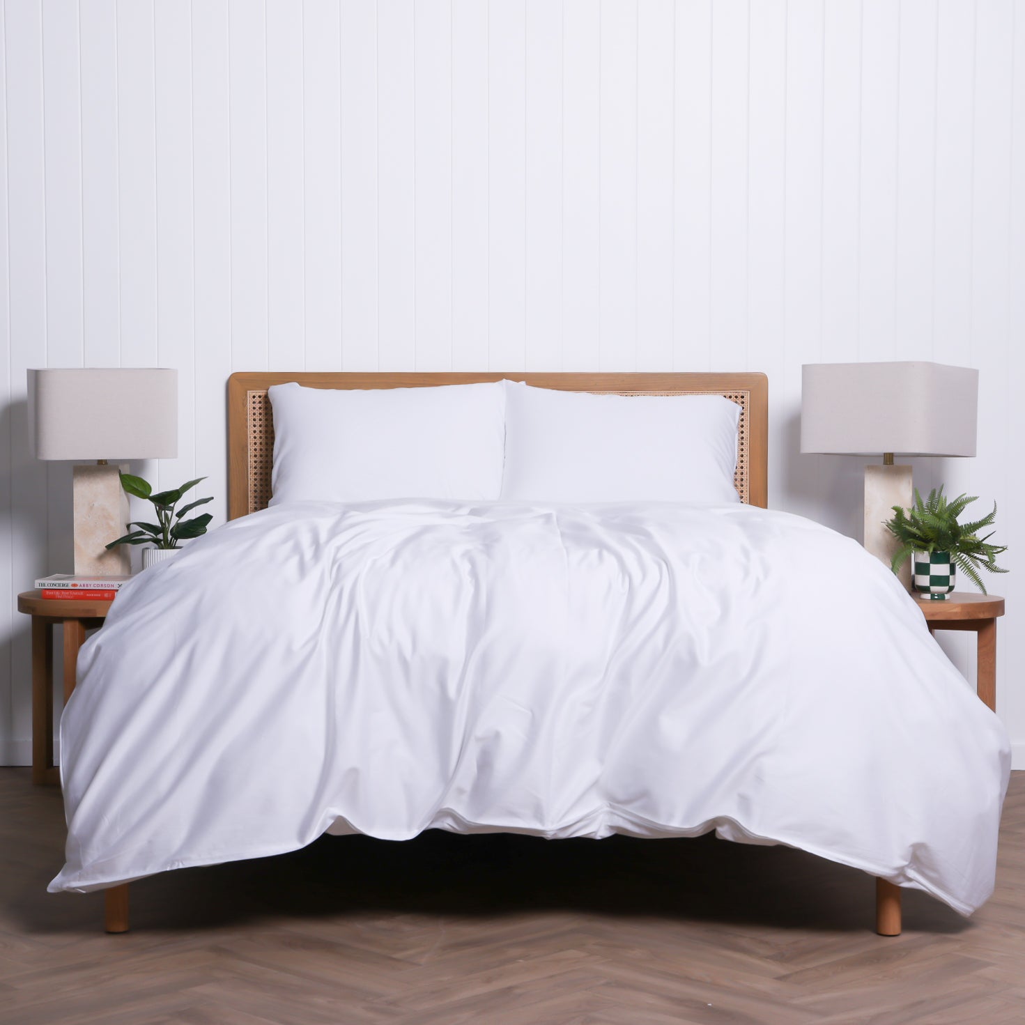 Whitehaven duvet set in crisp white, styled with rattan headboard and warm neutral lighting for a fresh, inviting bedroom look.