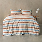 Striped bedding set on a bed with a side table in the background