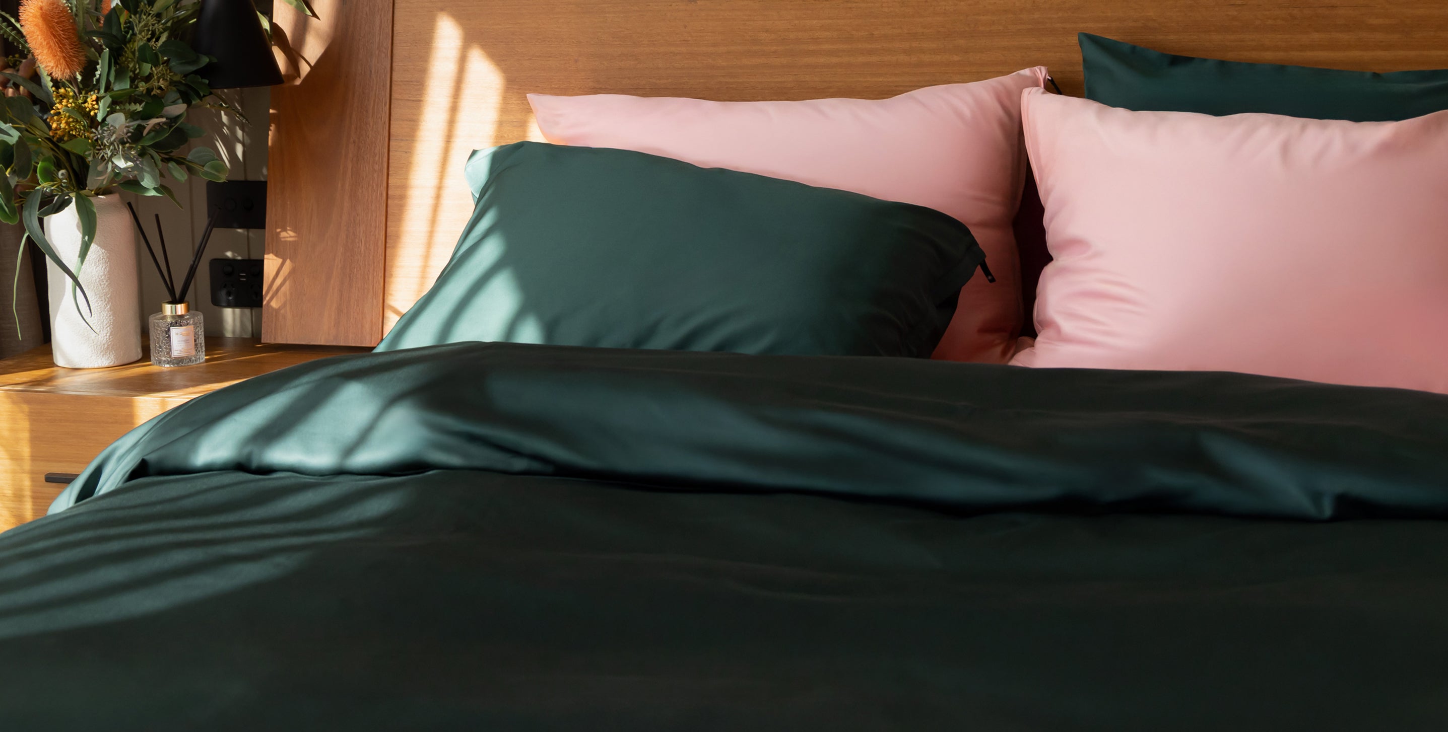 Bed with green and pink bedding and pillows, wooden headboard, and decorative items.