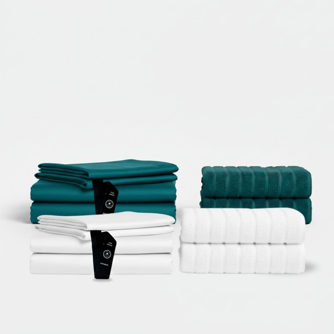Bedding sets and matching towels in teal and white neatly folded together.